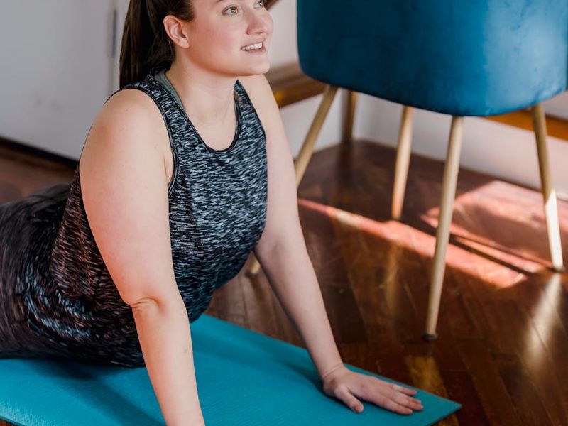 A person in a deep yoga stretch in a sunlit room.