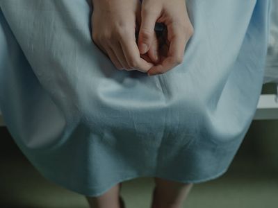 Person sitting calmly with hands on knees.